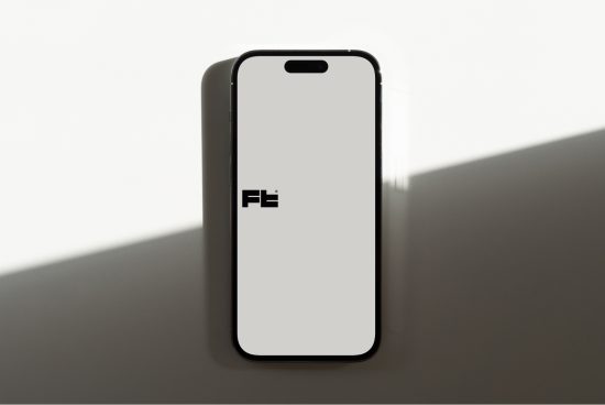 Smartphone standing on edge displaying blank screen with logo, ideal for Mockups, digital design, app presentation.